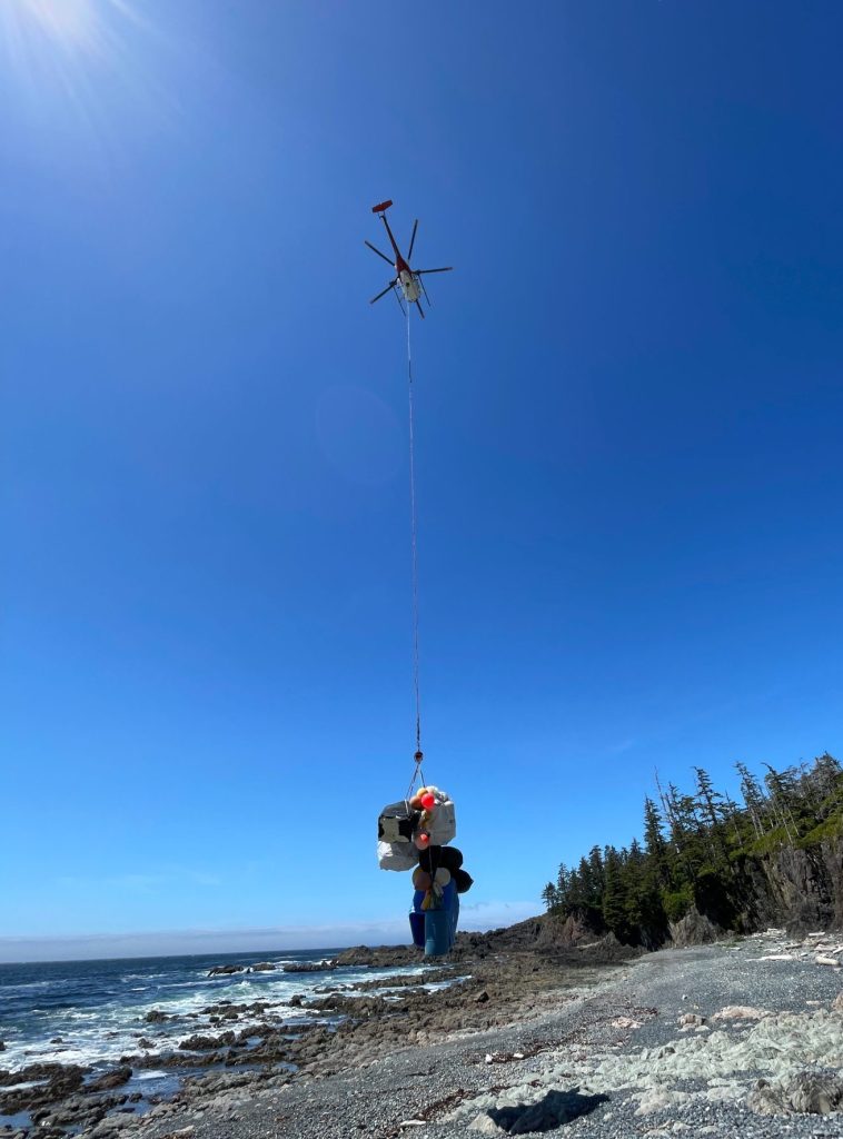 Helicopter lifting marine debris from a remote beach in Canada